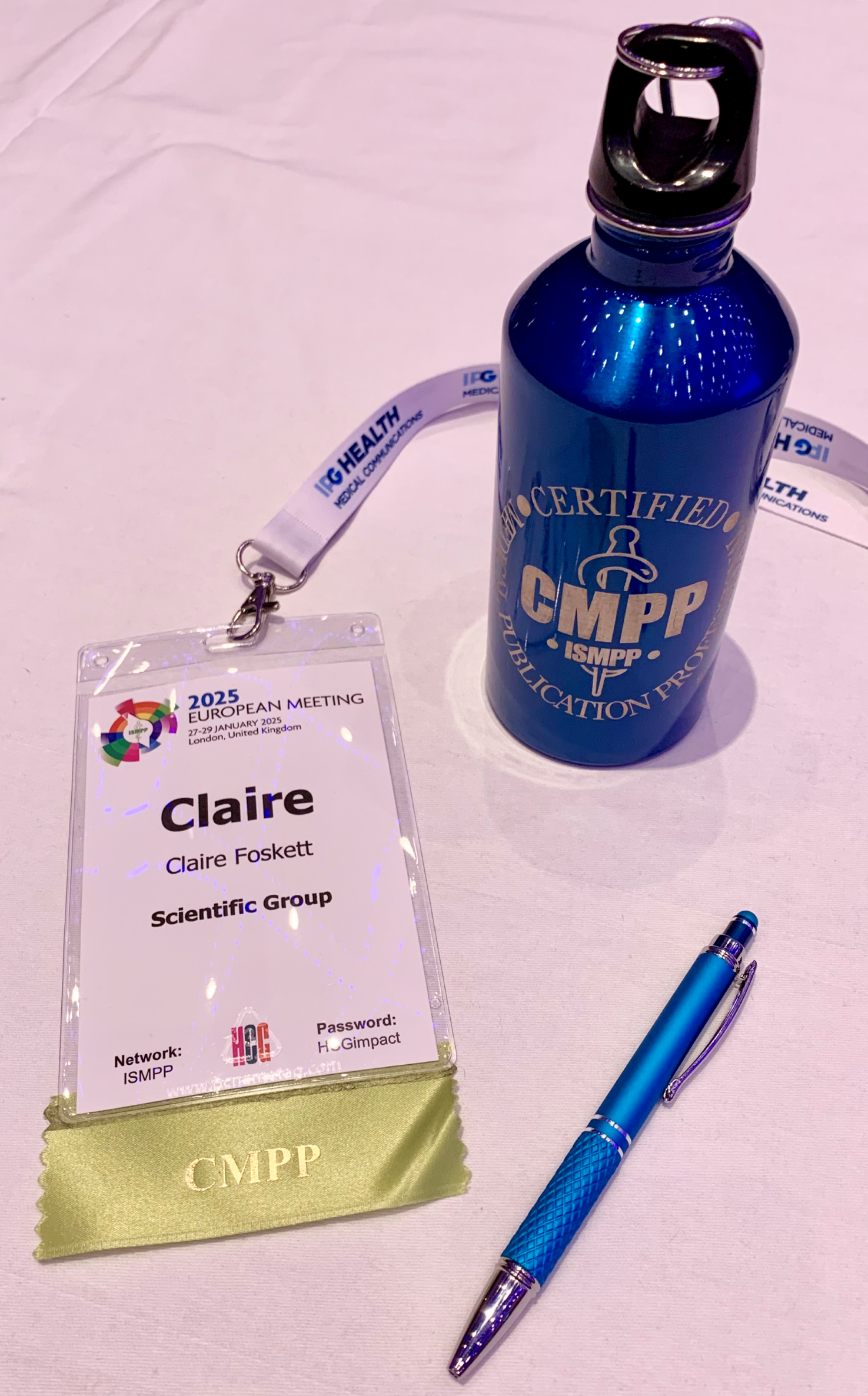 ISMPP 2025 Pass, pen and water bottle on a pink table